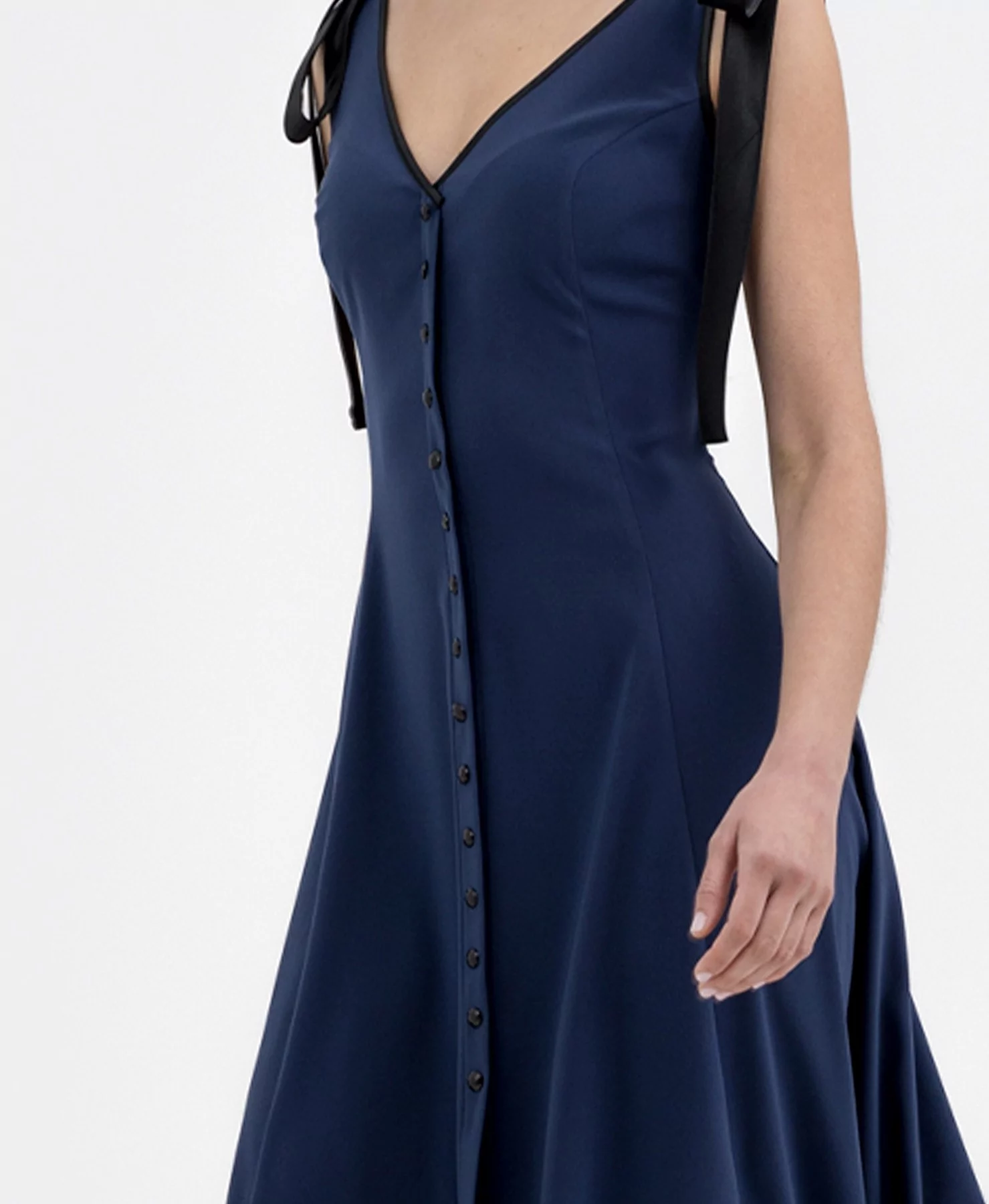 A deep blue midi dress that stands out for its decorative button design and satin bows on the straps