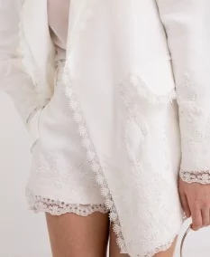 Close-up of the delicate lace embroidery on the white blazer, highlighting its elegance and sophistication.